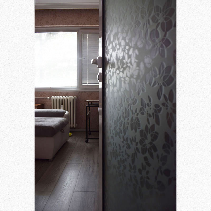 picture of a bedroom with open beautiful door that leads to the bedroom. We see high quality laminated floorq part of a Sectional Sofa and windos